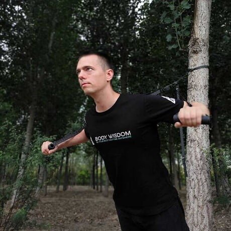 Man using the Sling Trainer wearing a Body Wisdom T-Shirt